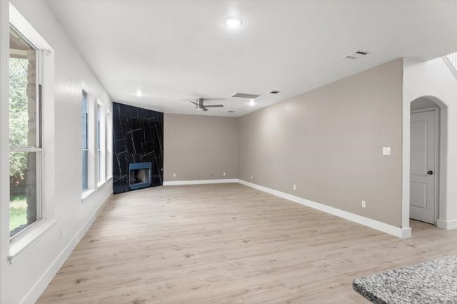 Unfurnished living room with light wood-style floors, a ceiling fan, a fireplace, arched walkways, and recessed lighting | Image 5