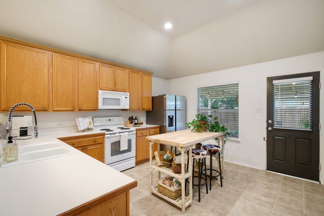 Kitchen featuring white appliances, lofted ceiling, and light tile patterned floors | Image 10