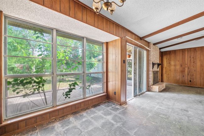 Unfurnished sunroom with plenty of natural light, a chandelier, and vaulted ceiling | Image 5