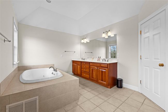 Full bathroom featuring visible vents, a sink, lofted ceiling, a jetted tub, and double vanity | Image 26
