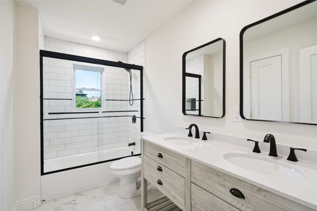 Bathroom with bath / shower combo with glass door, marble look tile flooring, and double vanity | Image 18