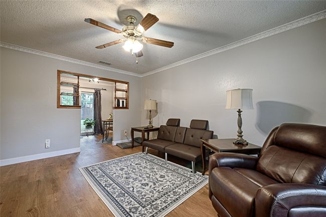 Living area with newly installed LVP floors and original curio shelves, separating the living and dining area. | Image 5