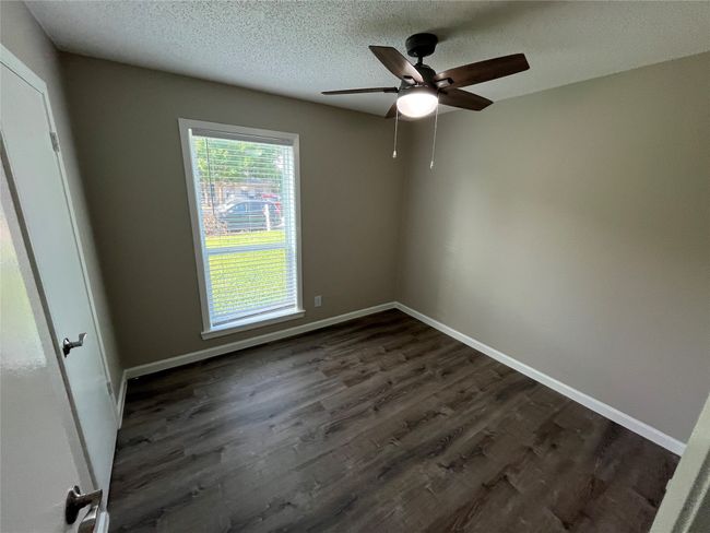 Spare room featuring dark wood finished floors, a textured ceiling, ceiling fan, and baseboards | Image 16