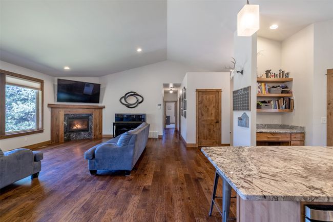 Living area featuring a glass covered fireplace, dark wood finished floors, lofted ceiling, baseboards, and recessed lighting | Image 10