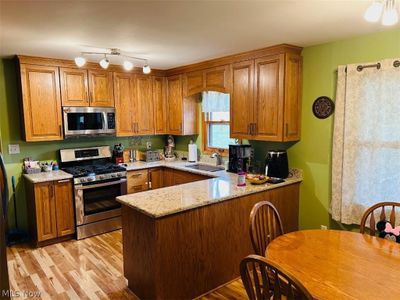 Kitchen featuring light hardwood / wood-style flooring, sink, appliances with stainless steel finishes, light stone countertops, and kitchen peninsula | Image 3