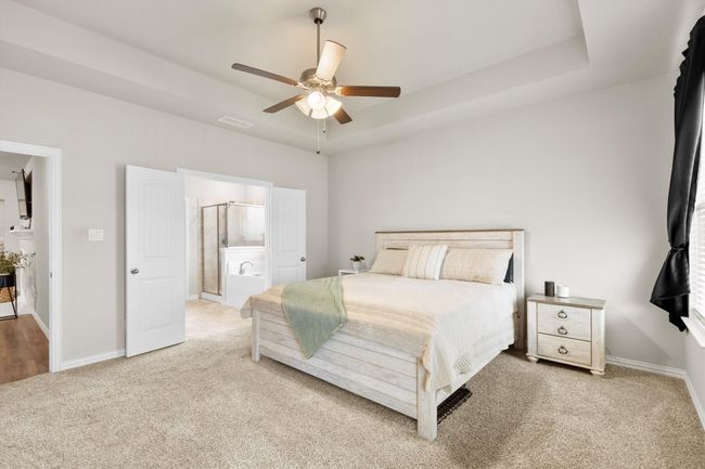 Bedroom with light colored carpet, ensuite bathroom, a ceiling fan, and a raised ceiling | Image 22