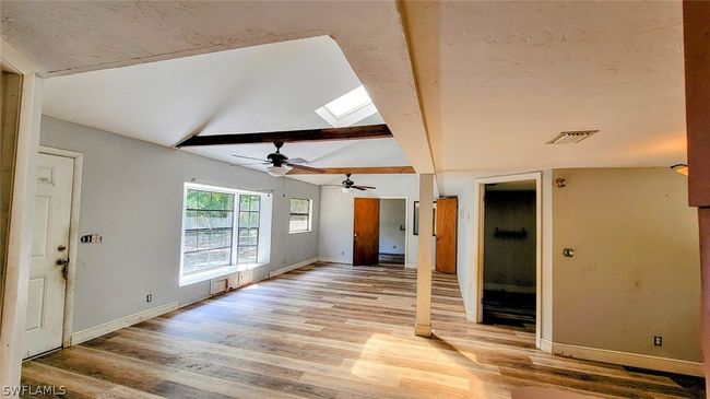Living room featuring ceiling fan, light hardwood / wood-style floors, and lofted ceiling with skylight | Image 9