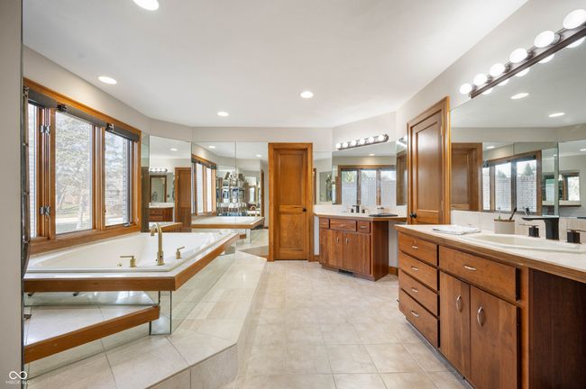 bathroom with a healthy amount of sunlight, two vanities, a garden tub, and a sink | Image 25