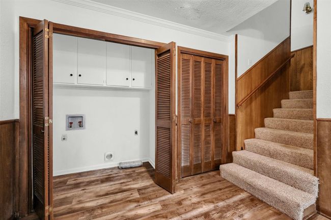 Laundry room featuring hookup for an electric dryer, cabinet space, hookup for a washing machine, light wood-type flooring, and a textured ceiling | Image 32