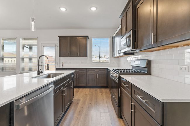 Kitchen with dark brown cabinets, a healthy amount of sunlight, appliances with stainless steel finishes, and a sink | Image 7