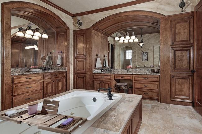 Spa-like bathroom features a large soaking tub, granite countertops and rich wood cabinetry | Image 19
