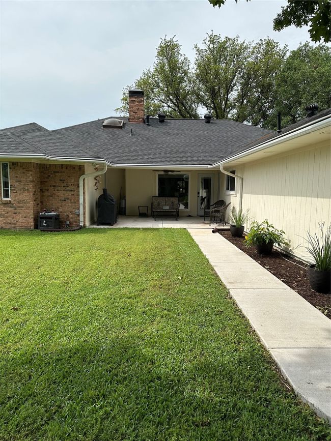 Back of property featuring a chimney, a yard, a patio area, and a shingled roof | Image 26