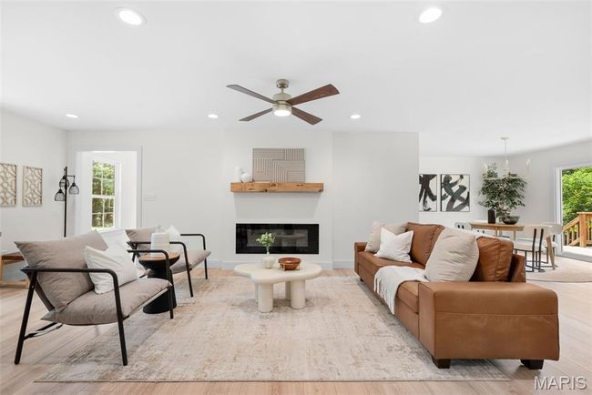 Living area with recessed lighting, light wood-style floors, a ceiling fan, and a glass covered fireplace | Image 12