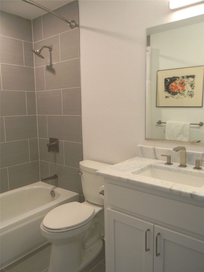 Upstairs guest bathroom featuring toilet, shower and tub combination and stone vanity top | Image 16