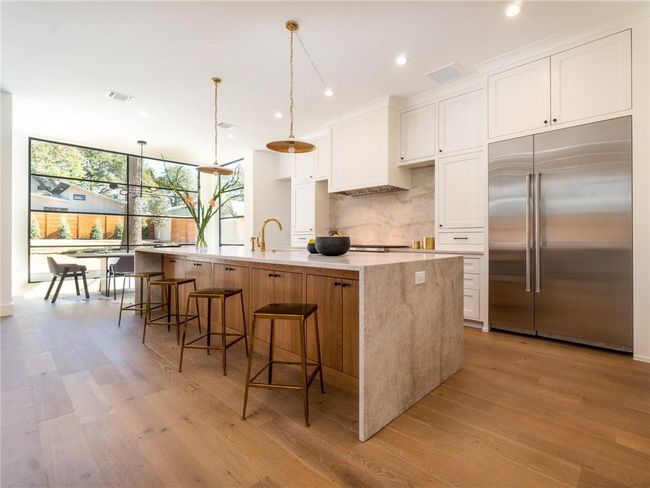 Kitchen featuring built in fridge, a wall of windows, tasteful backsplash, a spacious island, and white cabinetry | Image 4