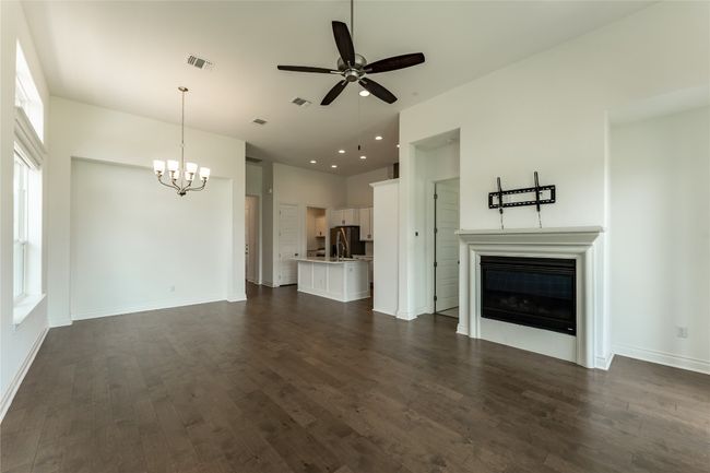 Unfurnished living room with a chandelier, ceiling fan, a glass covered fireplace, dark wood-type flooring, and recessed lighting | Image 21