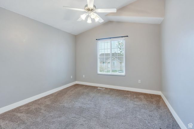 Carpeted empty room featuring lofted ceiling, baseboards, visible vents, and ceiling fan | Image 15