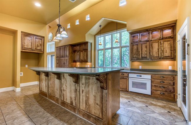 Kitchen with warm wood cabinetry and under-cabinet lighting. | Image 12