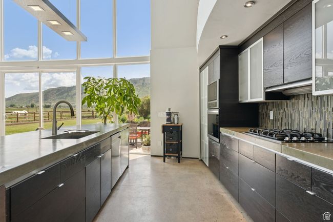 Kitchen featuring a sink, stainless steel appliances, a mountain view, backsplash, and finished concrete floors | Image 12