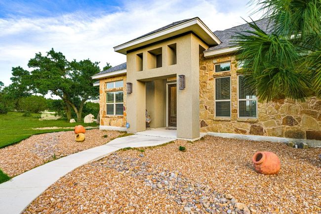 View of front of property featuring stone siding, stucco siding, and roof with shingles | Image 5