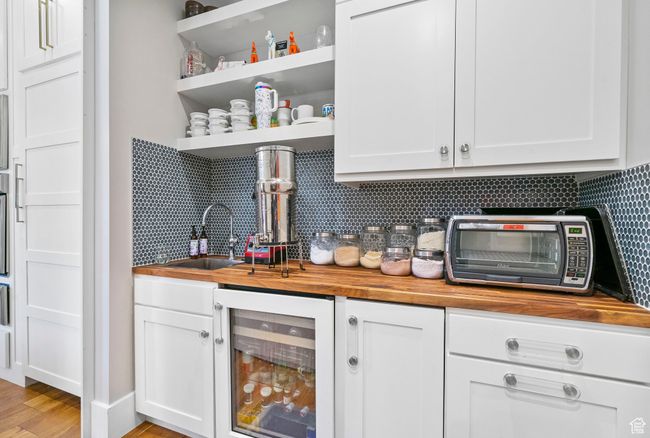 Bar featuring wet bar, a toaster, backsplash, light wood-style floors, and beverage cooler | Image 30