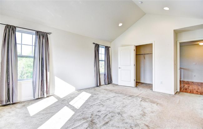 Primary bedroom with multiple windows, light colored carpet, recessed lighting, and high vaulted ceiling | Image 16