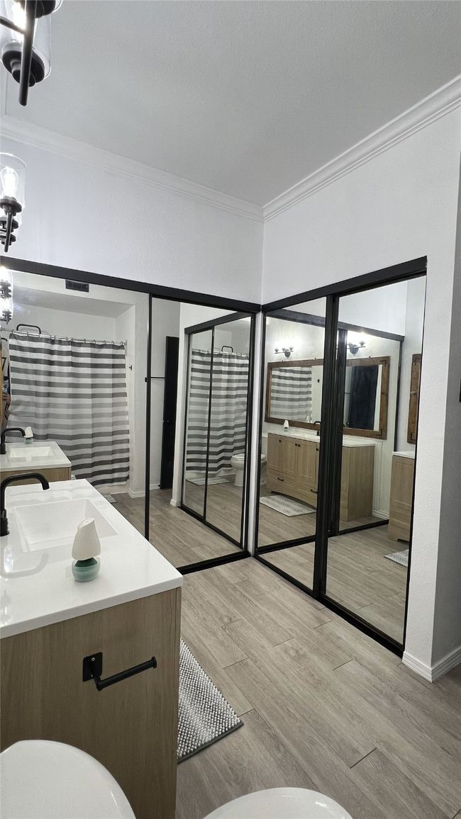 Full bath featuring toilet, baseboards, wood finished floors, crown molding, and vanity | Image 13
