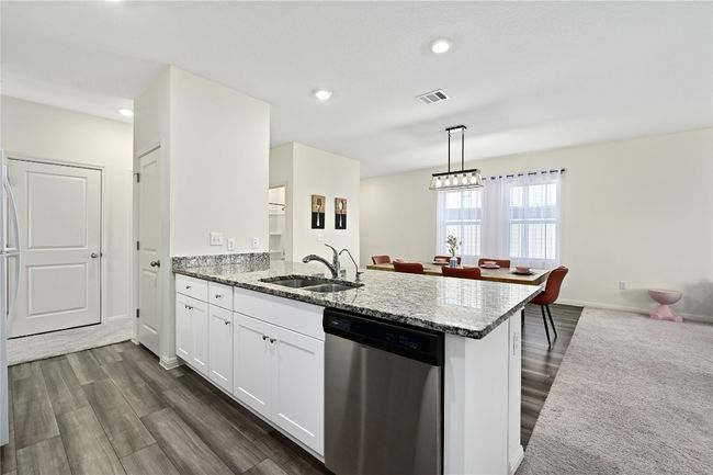 Kitchen featuring dishwasher, a sink, light stone countertops, a peninsula, and dark wood-style flooring | Image 18