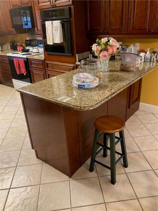 Kitchen with a kitchen breakfast bar, stove, wall oven, and light tile patterned flooring | Image 12
