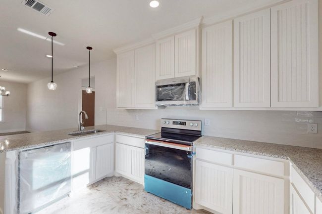 Kitchen with tasteful backsplash, a peninsula, visible vents, appliances with stainless steel finishes, and a sink | Image 15