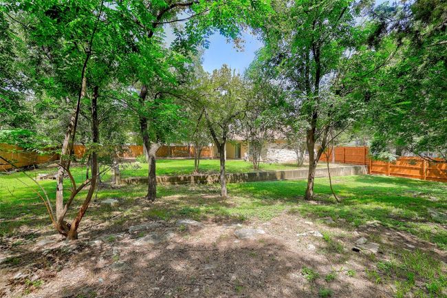 View of tree filled fenced backyard | Image 30