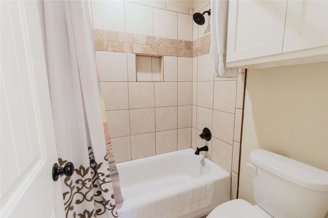 Bathroom with toilet and shower / bathtub combination with curtain | Image 12