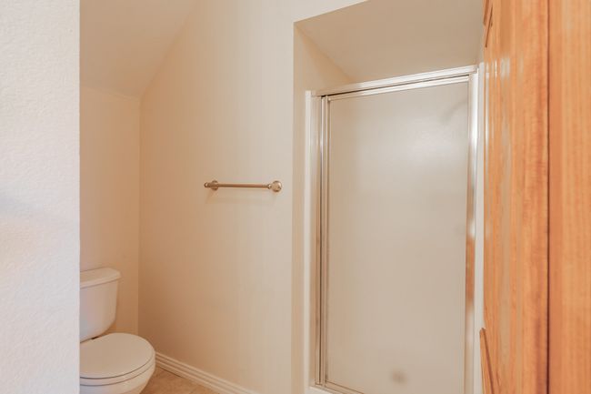 Bathroom featuring tile patterned floors, lofted ceiling, toilet, and a shower with shower door | Image 8