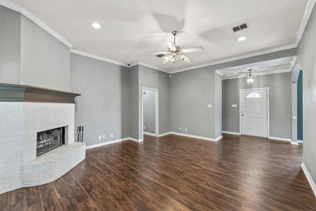 Unfurnished living room featuring ceiling fan, wood finished floors, a fireplace, recessed lighting, and crown molding | Image 4