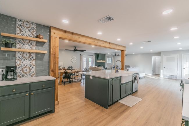 Kitchen with green cabinetry, open floor plan, recessed lighting, a ceiling fan, and light countertops | Image 5