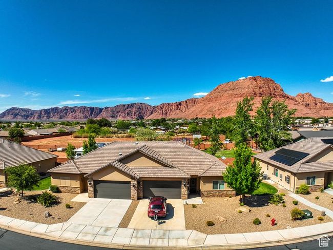 View of front facade with an attached garage, stone siding, driveway, and a mountain view | Image 4