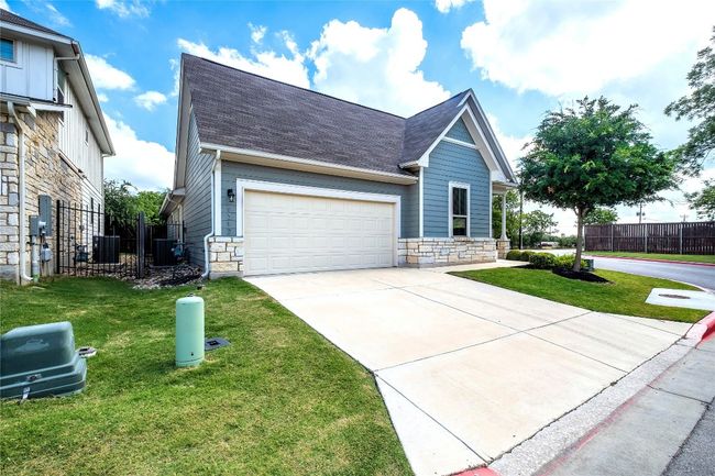 View of front of home featuring stone siding, driveway, roof with shingles, and a garage | Image 4