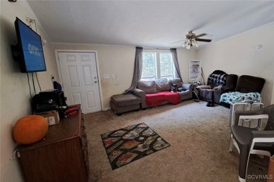 Carpeted living room with a textured ceiling and ceiling fan | Image 3