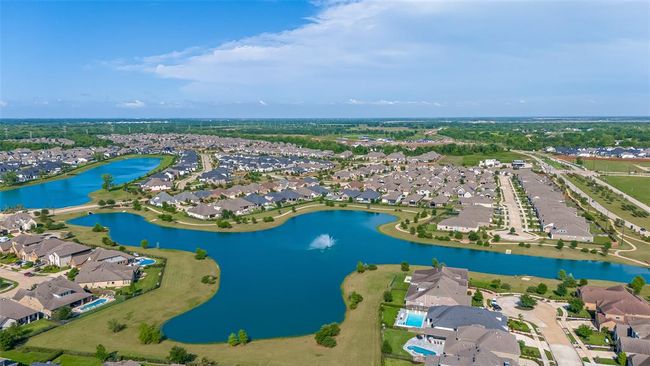 This aerial photo showcases a serene residential community with well-maintained homes, lush greenery, and scenic water features, creating a peaceful suburban atmosphere. | Image 46
