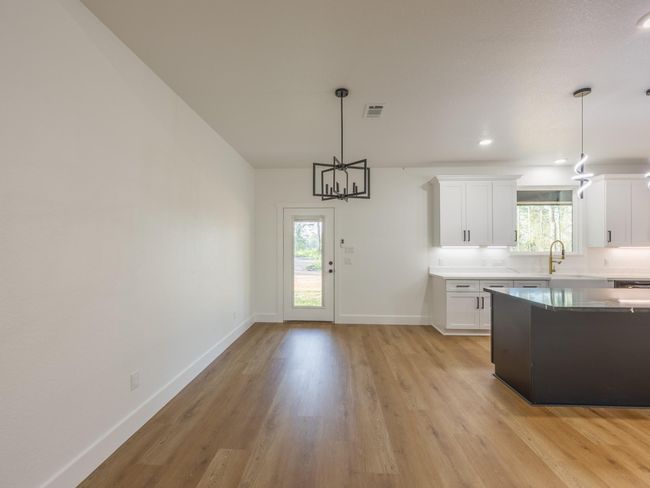 Enjoy meals with a view in this light-filled dining area just off the kitchen. Modern pendant lighting and a door leading to the backyard make indoor-outdoor dining a breeze. | Image 11