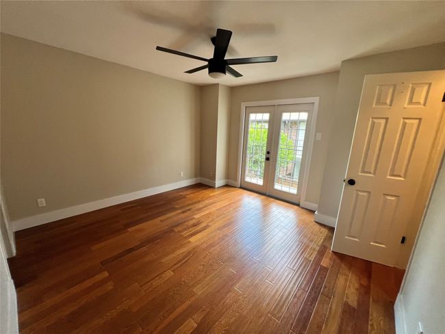 Spare room featuring french doors, dark wood-type flooring, baseboards, and a ceiling fan | Image 13