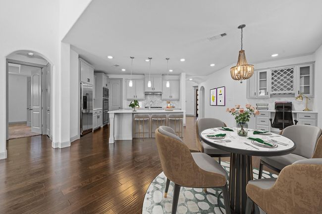 Dining area featuring dark wood-style floors, arched walkways, visible vents, and recessed lighting | Image 6