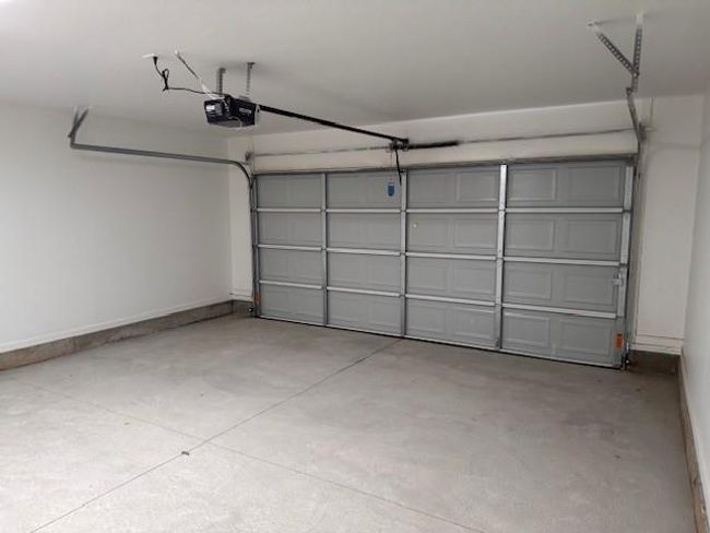 Garage featuring a garage door opener and baseboards | Image 38