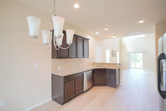 Kitchen featuring a peninsula, light wood finished floors, tasteful backsplash, fridge with ice dispenser, and light stone countertops | Image 7