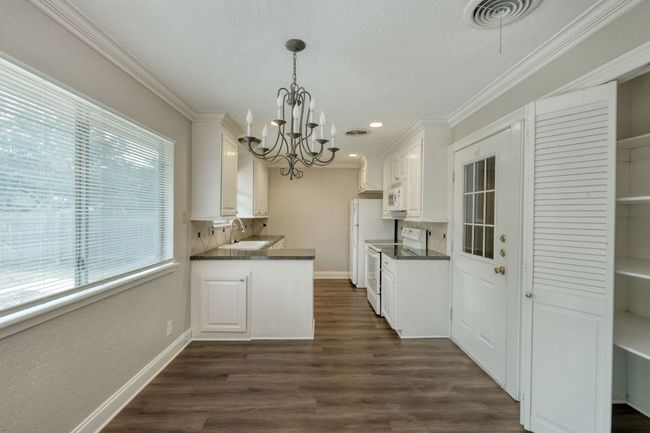 Kitchen featuring white appliances, dark countertops, a chandelier, backsplash, and crown​​‌​​​​‌​​‌‌​‌‌​​​‌‌​​‌‌​‌​​​​​‌ molding | Image 4