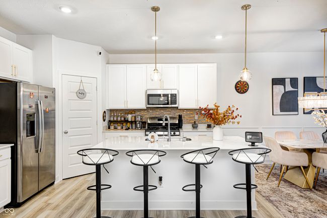 kitchen with light wood-type flooring, appliances with stainless steel finishes, light countertops, and a sink | Image 15