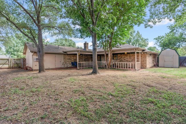 Rear view of property featuring a storage shed, a chimney, brick siding, and a gate | Image 25