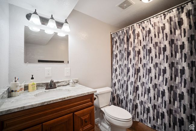 Bathroom featuring visible vents, toilet, curtained shower, and vanity | Image 16