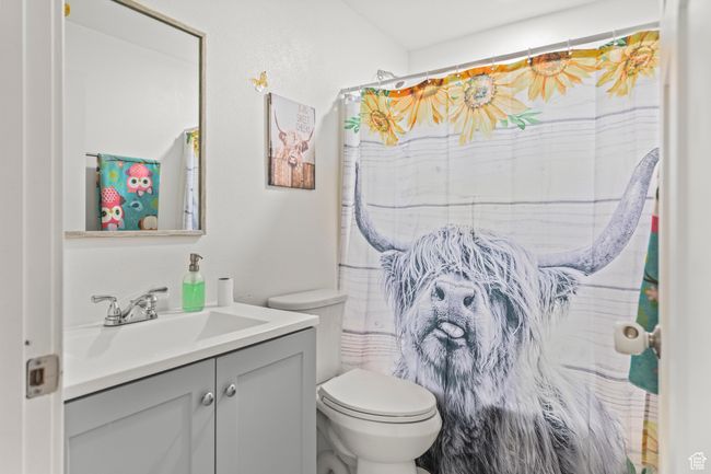 Bathroom with toilet, vanity, and curtained shower | Image 9