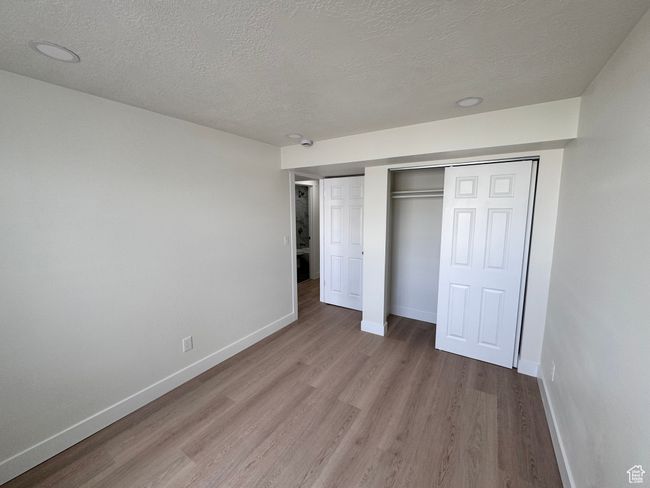 Unfurnished bedroom with a textured ceiling, wood finished floors, and baseboards | Image 33